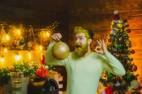 クリスマスボール、金の泡と屋内でハンサムなサンタの肖像画。冬服を着たハッピーサンタはクリスマスツリーの近くのクリスマスについて考えます。テーマクリスマス休暇と冬の新年. — ストック写真