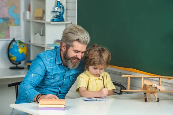 Padre che aiuta suo figlio a fare i compiti. Tutor privato per bambini. Ragazzo carino con insegnante in classe vicino alla scrivania della lavagna. — Foto Stock