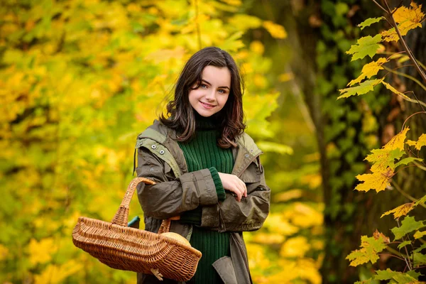 Mutlu genç kız gülümsüyor. Güzel bir genç kızın sonbahar portresi sepeti tutuyor.. — Stok fotoğraf