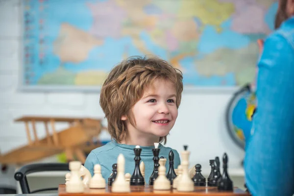 Vrolijk lachend jongetje aan tafel en opgewekte blijdschap tijdens het schaken. Kinderen vroege ontwikkeling. — Stockfoto