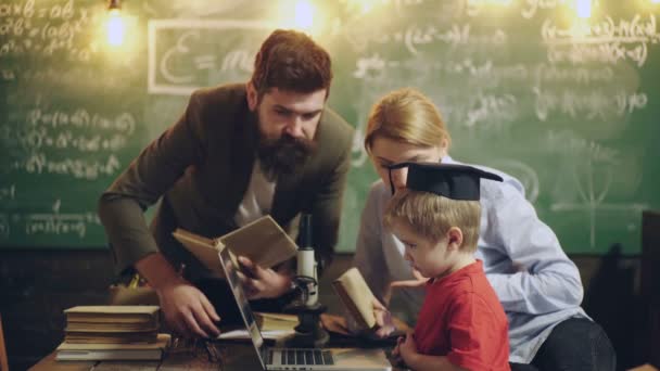A család együtt csinálja a házi feladatot otthon. Aranyos gyerek ül egy íróasztalnál.. — Stock videók