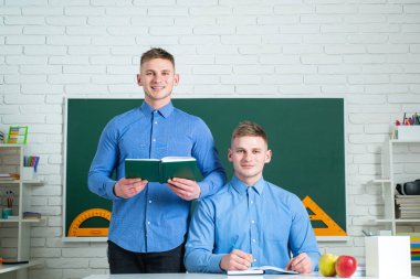 Üniversitede öğrenen kardeşler, açık bir kitap tutuyorlar..