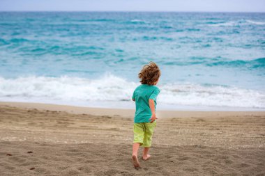 Tatlı çocuk yazın kumsalda koşuyor ve eğleniyor..