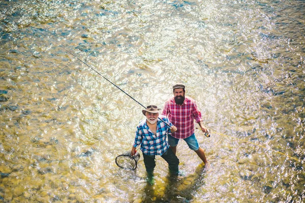Κομψοί μουσάτοι άντρες που ψαρεύουν. Χαλαρώστε στο φυσικό περιβάλλον. Απαγορεύεται το ψάρεμα. Χαρούμενη φιλία ψαράδων. Fishman πλεκτά περιστροφή στο ποτάμι περιμένει μεγάλα ψάρια. Πιάσιμο ψαριών. — Φωτογραφία Αρχείου