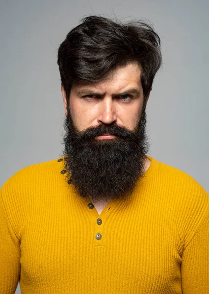 Portrait d'un bel homme sérieux avec barbe et moustache, regarde sérieusement, isolé sur un mur gris. — Photo