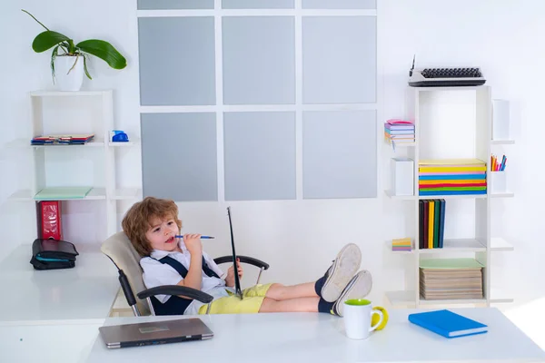 Kleiner Junge Geschäftsmann, der sein Unternehmen aus der Ferne regiert, wie ein Freiberufler. Geschäftsmannskind arbeitet an seinem Arbeitsplatz im Büro. — Stockfoto