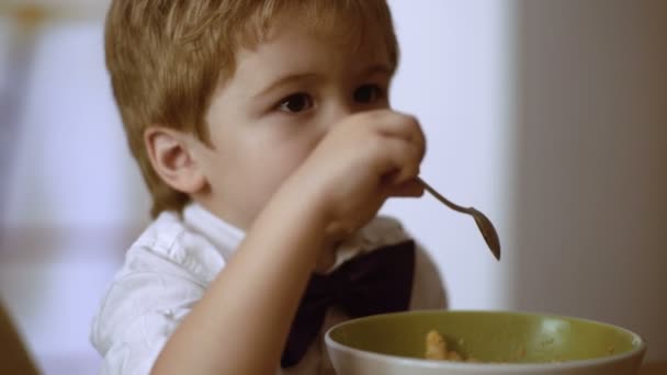 O pequenote está a gostar do mingau. Miúdo engraçado comer mingau com leite — Vídeo de Stock