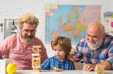 Büyükbaba ve tatlı küçük oğlu evde eğleniyor. Erkek ailesi. Büyükbaba, baba ve oğul evde Jenga oynuyorlar..