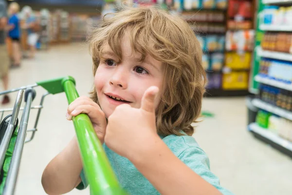 Criança no supermercado. Rapaz com um carrinho de compras. — Fotografia de Stock