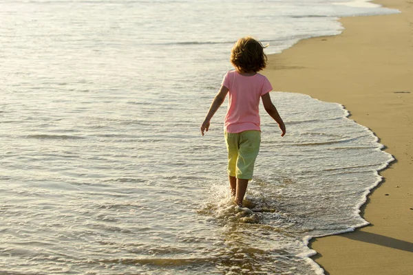 Niño jugando y divirtiéndose en la playa en el mar azul en verano. Océano azul con wawes. — Foto de Stock