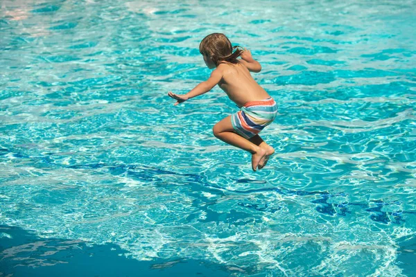 Kinderspringen in het zwembad. Kind heeft plezier op zomervakantie. — Stockfoto