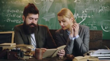 Öğrenciler eski okul sınıfında profesörle ders çalışıyor. Erkek profesör sınıftaki kız öğrencilere açıklayıp yardım ediyor..