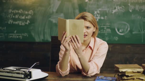 Студентка колледжа с книгой, сидящая за столом в классе перед доской. — стоковое видео