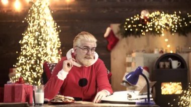 Komik Noel Baba şöminenin yanında oturuyor ve Noel ağacı Noel için hazır..