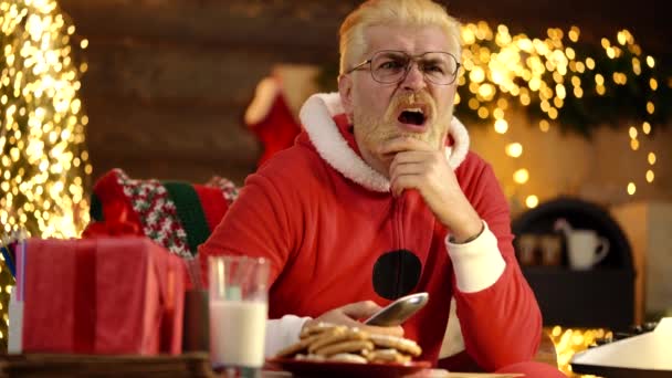 Emocionado Santa Claus en casa ver tv celebración de control remoto cerca del árbol de Navidad. — Vídeos de Stock