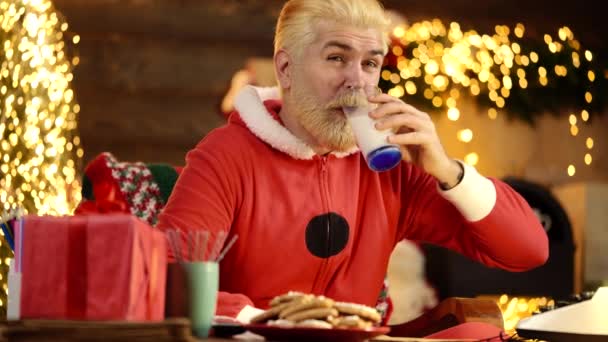 Komik, modern Noel Baba evde Noel ağacının yanında süt içer. Yeni Yıl Tatili. — Stok video