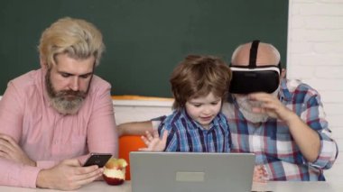 Evde eğitim. Çocuk eğitim ve evde eğitim. Teknoloji eğitimi konsepti. İnternetten öğreniyorum. Baba, büyükbaba VR gözlüklü ve oğlu evde çalışıyor ve ev ödevi yapıyor..