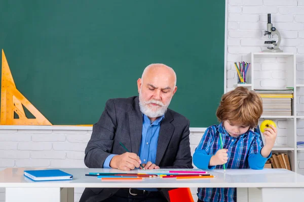 Un nonno e un figlio stanno imparando in classe. Studente e tutoraggio concetto di istruzione. Torniamo a scuola. Vecchi e Giovani. Giorno di insegnanti. — Foto Stock