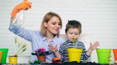 Anne ve oğul yazın ekilen çiçekleri suluyorlar. Fidye kavramı.