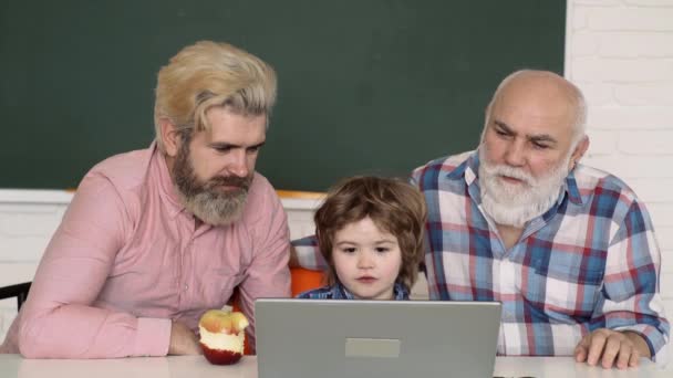 Drie generaties actieve mannen die computerspelletjes spelen in de woonkamer. Gelukkige multi generatie familie. Vaderdag. Vader, grootvader en zoon studeren thuis huiswerk. Basisschooljongen. — Stockvideo