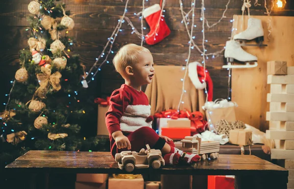 クリスマスクリスマスクリスマスの冬の休日の概念。クリスマスギフトボックス付きの幸せな子供。自宅でクリスマスにカメラを見て楽しい赤ちゃん。クリスマスツリーによって装飾的なおもちゃのボールを見て肖像幸せな子供. — ストック写真