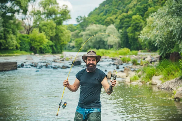 Hombre relajante y la pesca junto al lago. Diversión y relax. Pesca de agua dulce lago estanque río. Sólo hazlo. Pescador en equipo de pesca sombrero. Hombre relajante naturaleza fondo. — Foto de Stock