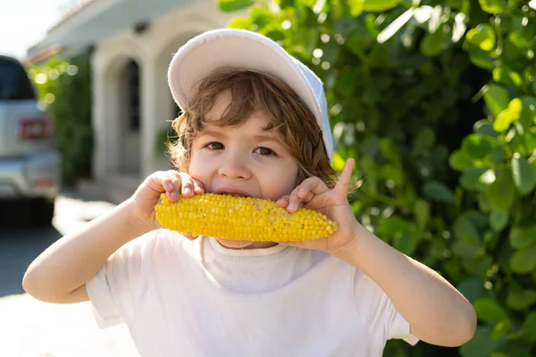 Rapaz feliz a comer milho na espiga. Conceito de agricultura e culturas de Outono. — Fotografia de Stock