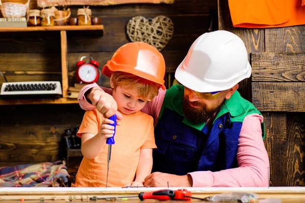 Father teaching son to use screwdriver and screw.