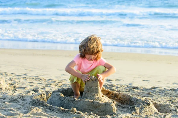 Kumsalda kumdan kalesi olan bir çocuk. Çocuklar yaz tatili. — Stok fotoğraf
