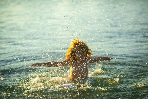 해가 지면 파도 속으로 뛰어드는아이. 가족을 위한 해상 휴가. 여름휴가 때 바다에 떠 있는 어린 소년. — 스톡 사진
