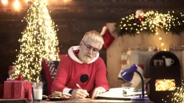 Kötü Noel Baba için dilek listesi. Modern Noel Baba tahta evinde sihirli dilek listesi okuyor. Noel 'in büyüsü.