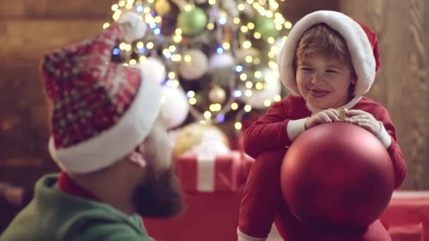 父と息子はクリスマスツリーの近くで話している。父親と子供は家でクリスマスを祝う。冬休み. — ストック動画