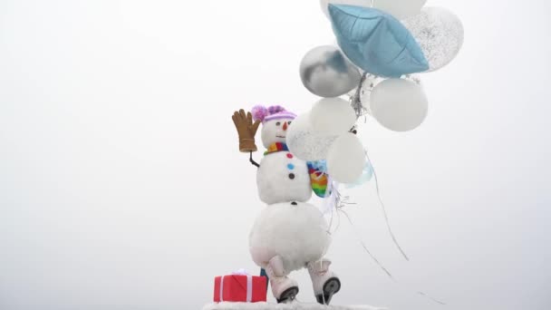 Retrato de invierno de un joven y hermoso hombre de nieve. Muñeco de nieve feliz con el regalo de pie en invierno blanco paisaje de Navidad. — Vídeo de stock