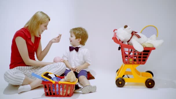 Mor och son spelar shopping. Mamma lär sin son att räkna pengar. leende liten pojke leker butik med mamma. — Stockvideo