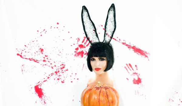 Beautiful young woman in bunny ears with pumpkin. Bloody halloween. Sexy woman bunny rabbit. Girl with pumpkin. Happy Halloween. Cute girl. Halloween costume party. Bloody white background.