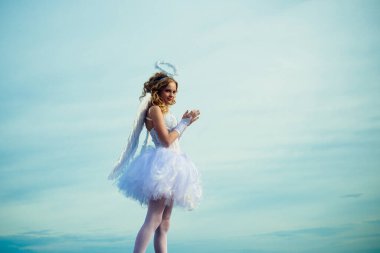 Beyaz elbiseli ve kanatlı sevimli kıvırcık kız. Melek gibi bir kız. Sihirli anın tadını çıkarıyorum. Genç Melek Eros. Cennet.