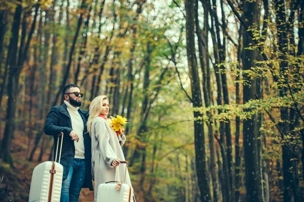 Podzimní pár. Venkovní módní fotografie mladých lidí s podzimními listy a kufříkem. — Stock fotografie