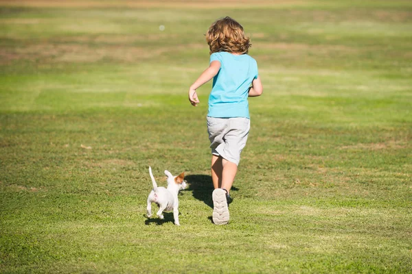 Happy kid courir avec un chien en plein air. — Photo