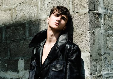 Modaya uygun bir adam. Moda adamı duvarın yanında duruyor..