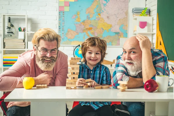 Chlapec si užije čas se starším dědečkem a mladým otcem. Rodinný strom. Jenga hry pro rodinu. — Stock fotografie