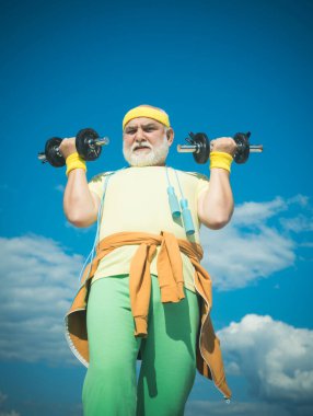 Kıdemli sporcu dambılları kaldırıyor. Yaşlılık sağlığını gevşetmek için bir bahane değildir. Yaşlı adam egzersizi..