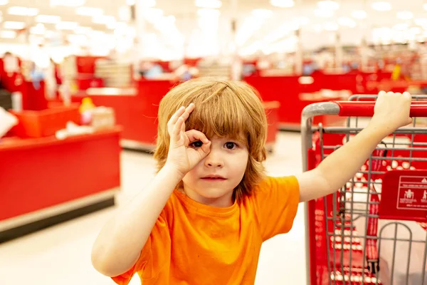 Радостный мальчик в супермаркете покупает овощи. Здоровое питание для детей. Забавные покупки. Симпатичный ребенок с улыбкой — стоковое фото