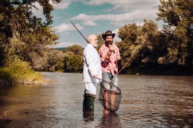 Göldeki adamlar. Balıkçı takımı. Mutlu neşeli insanlar. Balıkçılık dikkatli ve tam olarak hazır olmayı gerektirir. İki erkek arkadaş birlikte balık tutuyor. Arkadaşız. Erkeklerin uçan balık hobisi.
