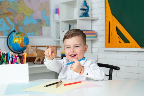 小学生の男の子。家庭でのレッスン中に宿題を勉強している幸せな小さな子供。授業中の生徒。学校に戻ると幸せな子供たちの時間. — ストック写真