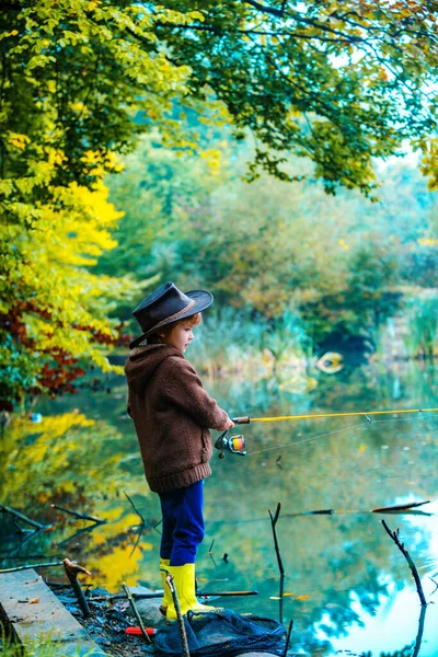 Ребенок учится рыбачить, держит удочку на озере. Парень с удочкой. Дети США. — стоковое фото