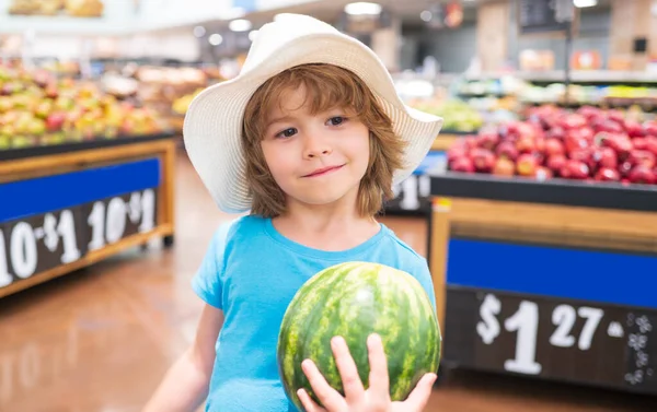 Bambino nel supermercato tenere anguria, comprare frutta e succo di frutta. Negozi di alimentari per bambini. Ragazzino che sceglie verdure fresche nel negozio locale. Vendita, consumismo e concetto di bambini. — Foto Stock