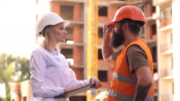 Il responsabile della costruzione controlla il processo di lavoro nel settore delle costruzioni. Un ingegnere donna comunica con un costruttore in un cantiere. Concetto costruzione. — Video Stock