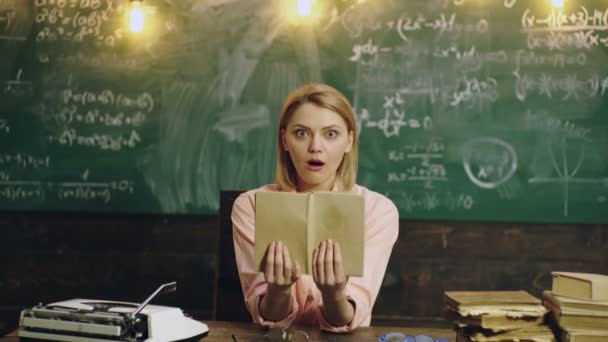 Estudiante estudiando en pizarra. Retrato de mujer joven sorprendida sosteniendo libro contra pizarra en classoom. — Vídeos de Stock