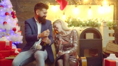 - Mutlu yıllar. Evdeki Noel ağacının yanında şampanya şişesi açan adam. Genç çift Noel 'in tadını çıkarıyor..