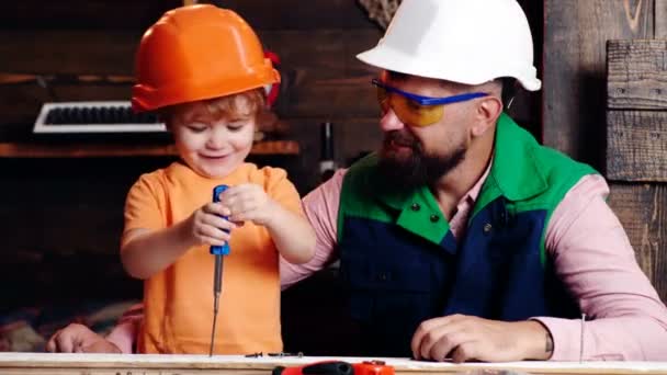 Bouw van vader en zoon in de garage. Kleine zoon helpen zijn vader met het bouwen van werk. — Stockvideo